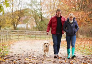 Couple walking their dog on an autumn path