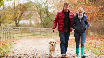 Couple walking their dog on an autumn path