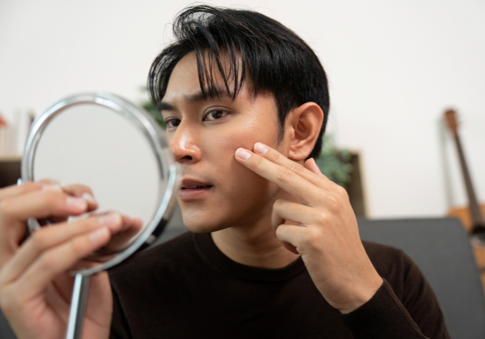 Man inspecting skin in a small mirror.