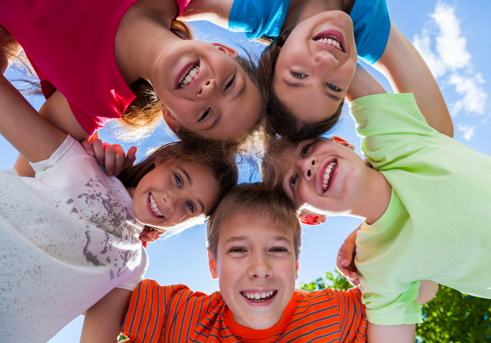 Happy children gathered in a circle and a clear blue sky behind them