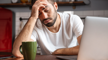 Tired man working on a laptop.