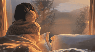 Woman looking out a window at a winter scene.