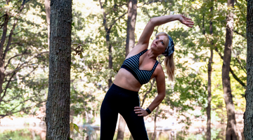 A woman stretching outdoors surrounded by trees