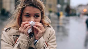 a woman using a tissue to blow her nose