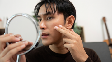Man inspecting skin in a small mirror.