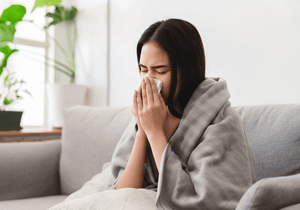Ill woman blowing nose in tissue. 