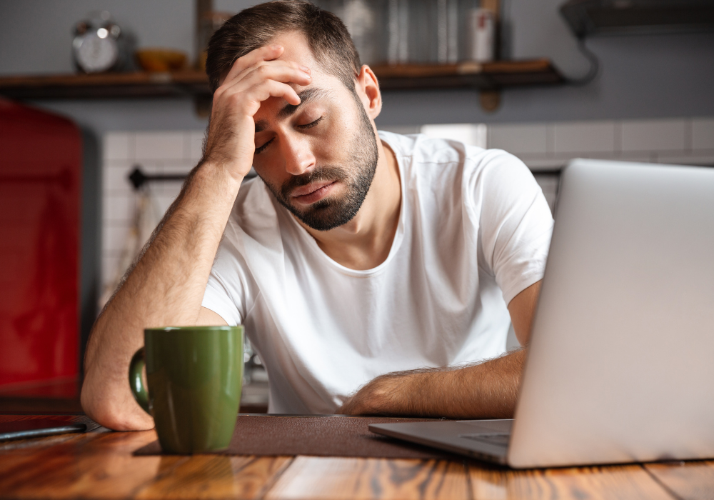Tired man working on a laptop.