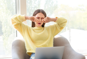 Tired woman working on a laptop.