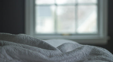 Cozy white bed in front of window.